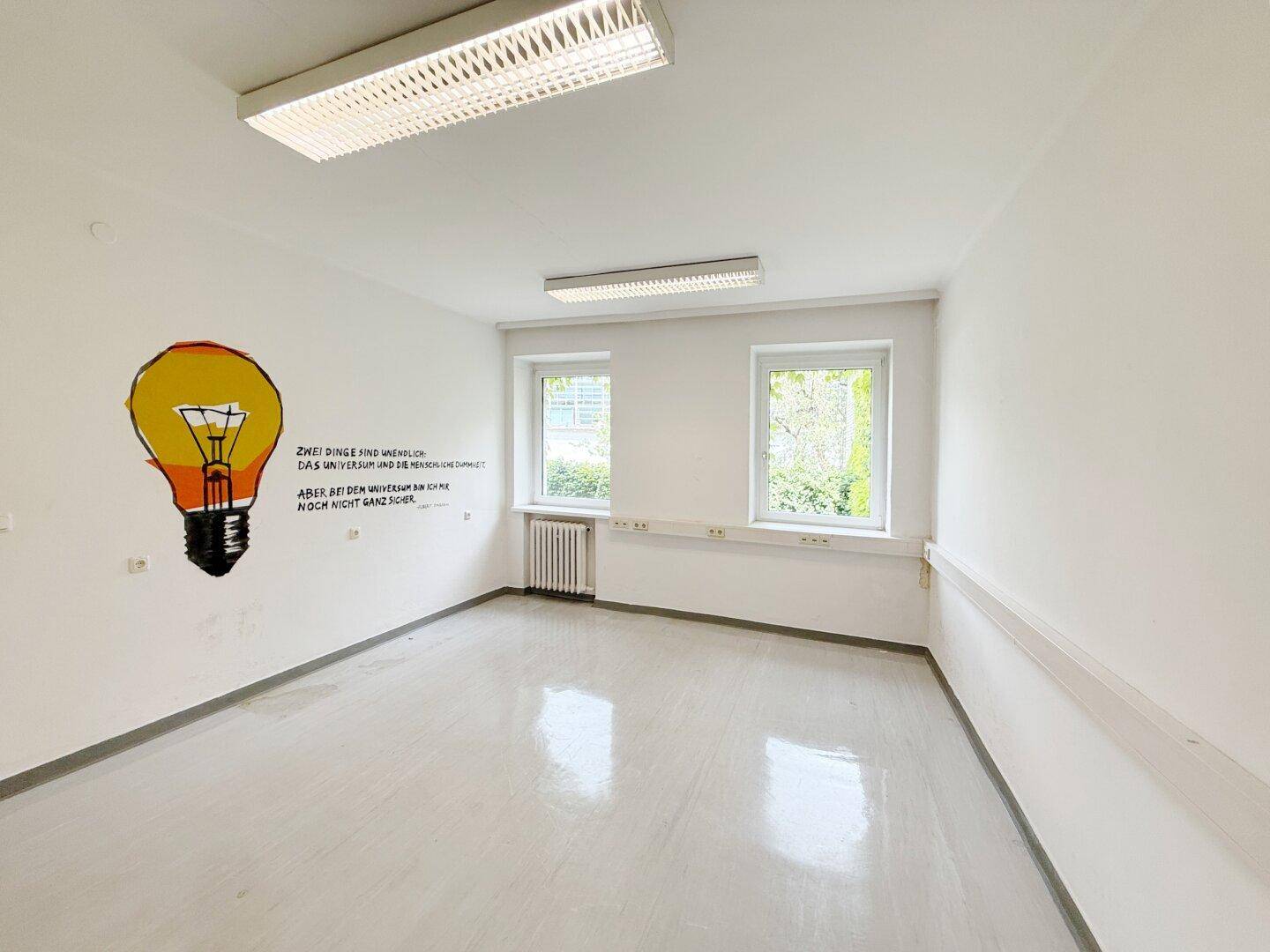 Heller Büroraum mit weißen Wänden, glänzendem Boden und kreativer Wandmalerei.
