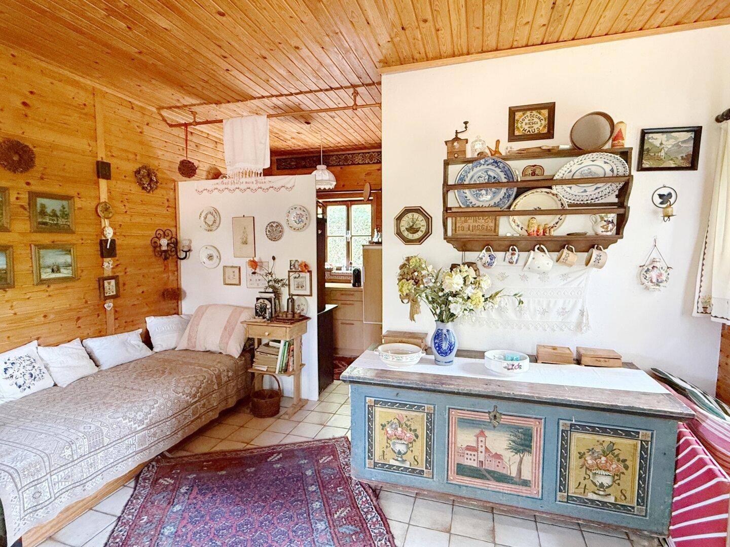 Gemütlicher Wohnbereich im Landhausstil mit Holzwänden, Fliesenboden und dekorativen Elementen.