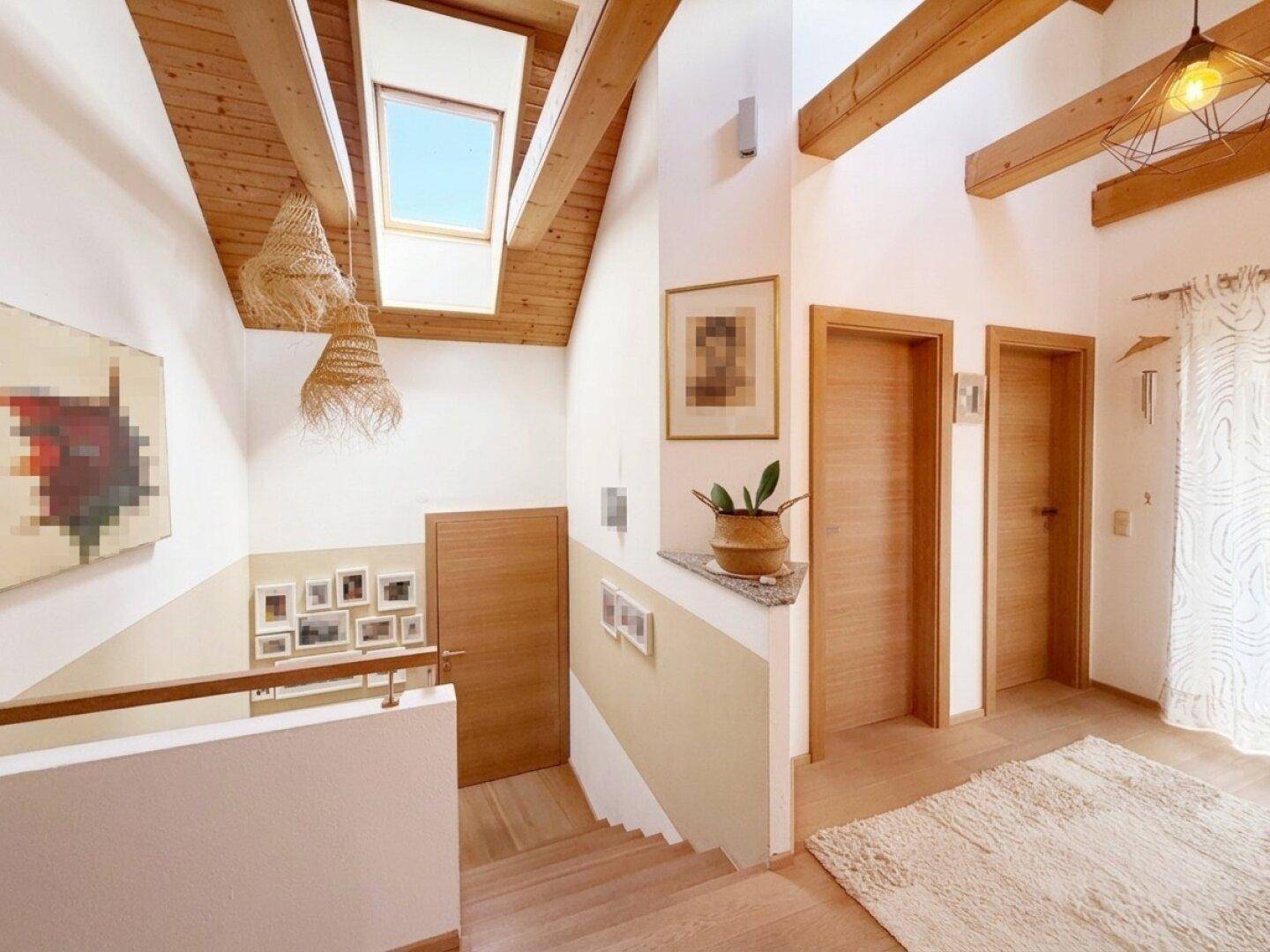Heller Treppenaufgang mit Holzbalken, Dachfenster und Holztreppe für viel Tageslicht.