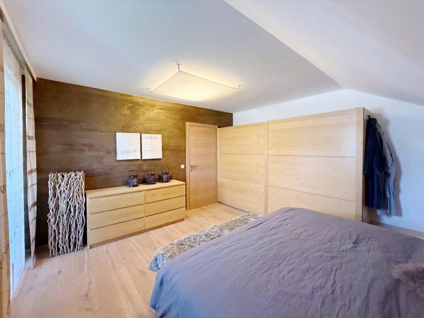 Schlafzimmer mit Holzboden, Einbauschrank und dekorativer Wandgestaltung im Dachgeschoss.