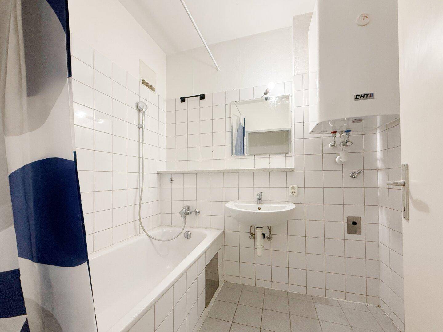 Badezimmer mit Badewanne, Waschbecken und Wandfliesen in Weiß.