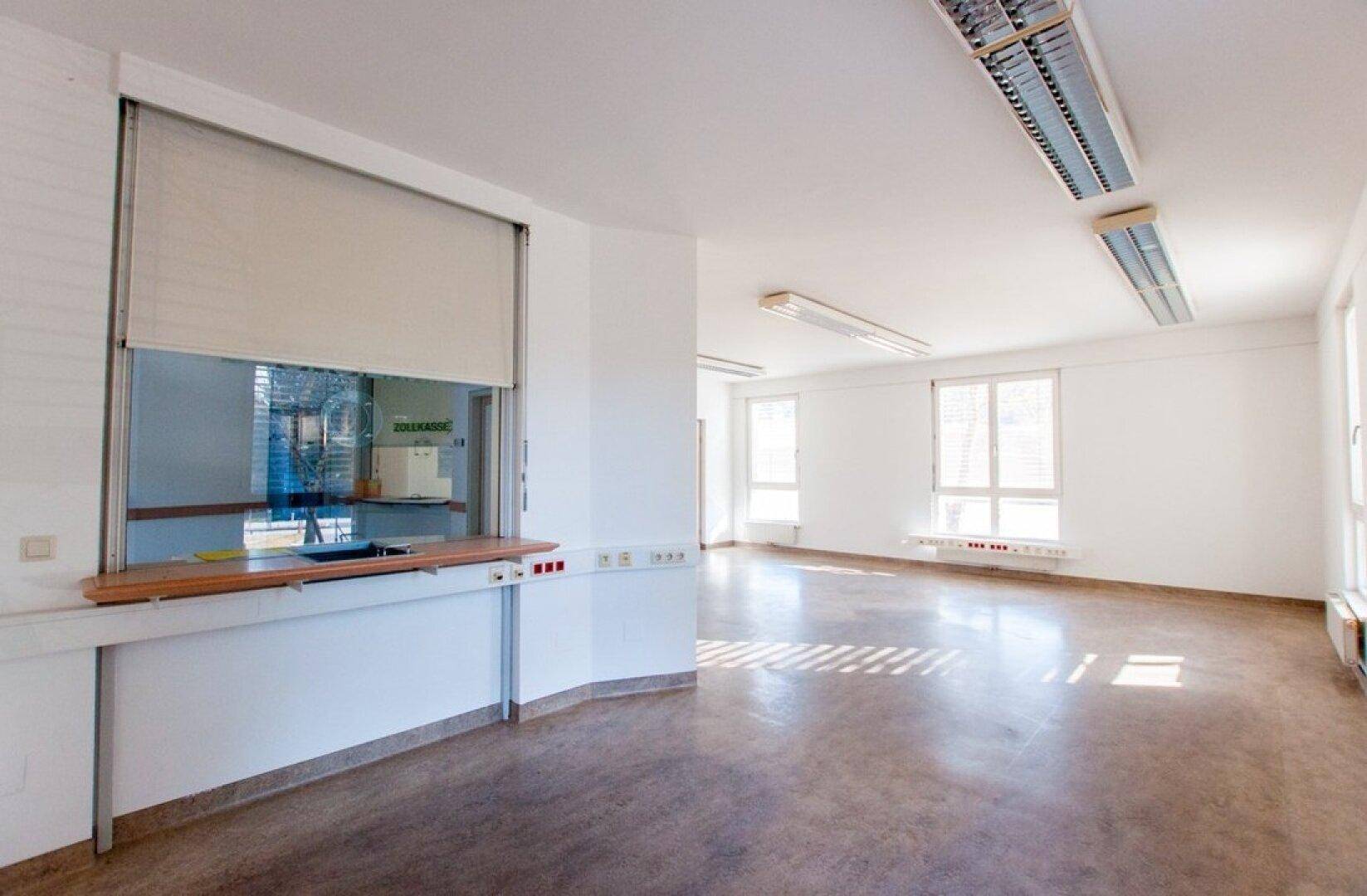 Geräumiges Büro mit Empfangsbereich, großen Fenstern und viel Tageslicht.