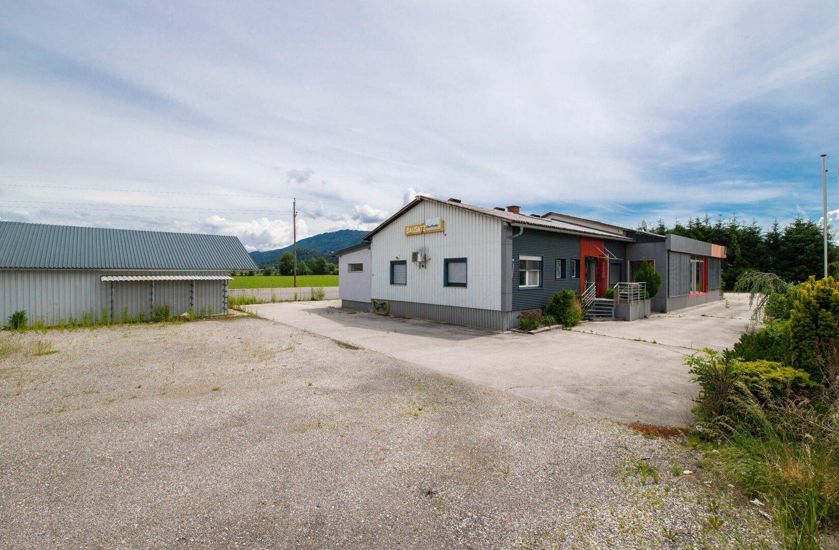 Geschäftsgebäude mit angrenzender Schotterfläche und Blick auf die weite Landschaft im Hintergrund.