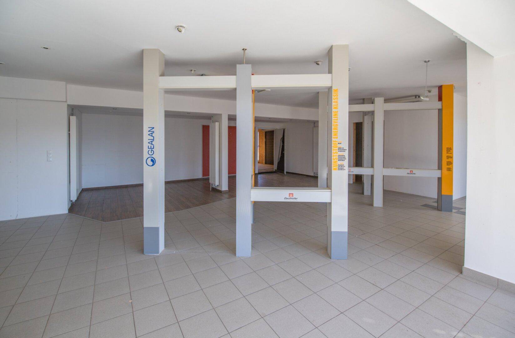 Heller Verkaufsraum mit Fliesenboden und großen Fensterfronten, ideal für Präsentationen.