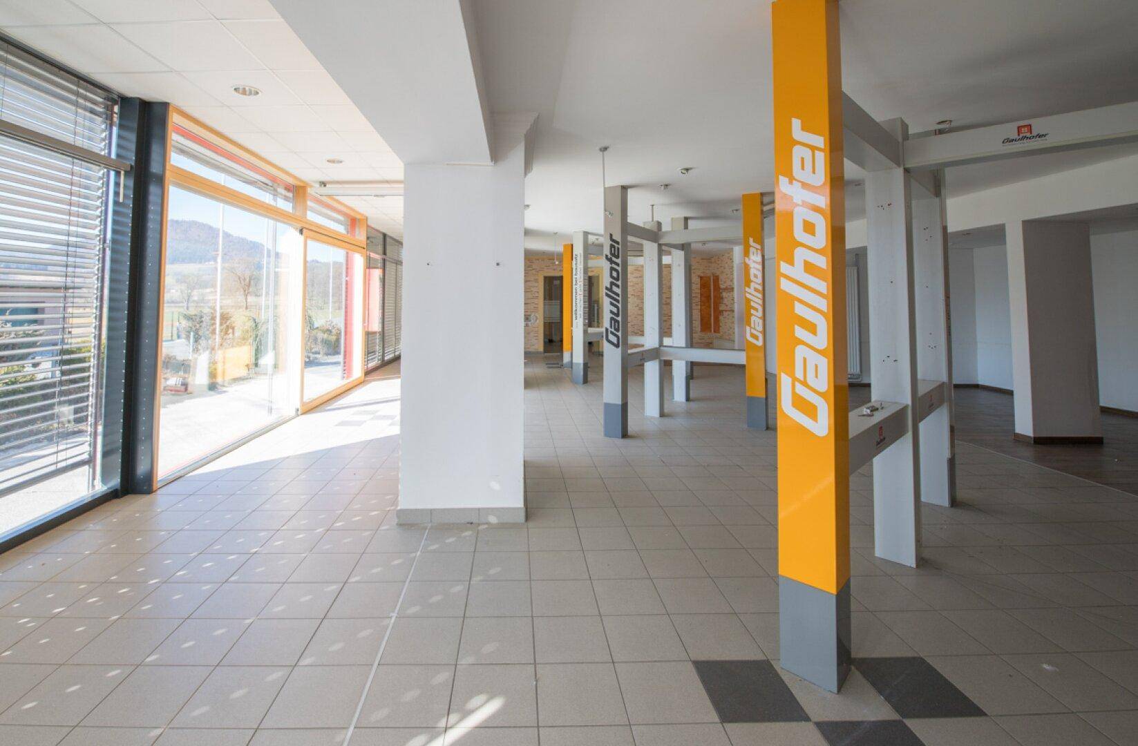 Weitläufiger Verkaufsraum mit Fliesenboden und viel natürlichem Licht, bietet flexible Gestaltungsmöglichkeiten.