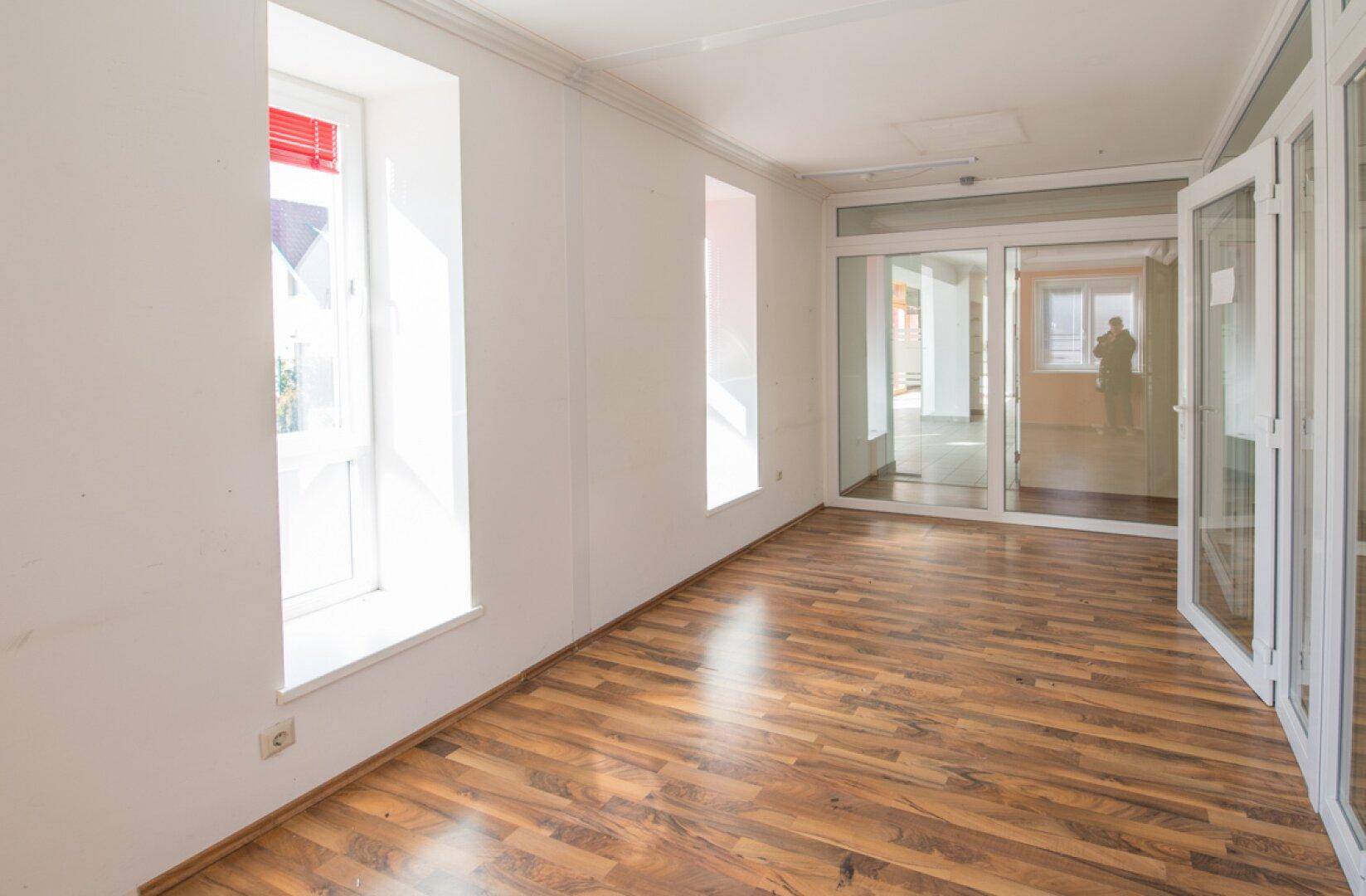 Helles Büro mit Laminatboden und großen Fenstern, bietet angenehme Arbeitsatmosphäre.