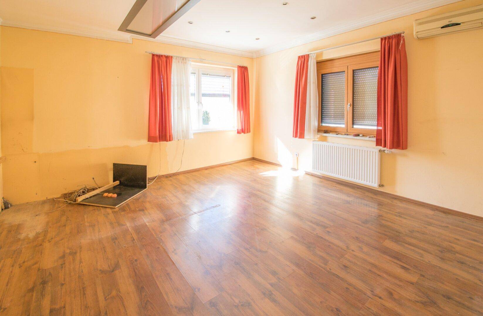 Geräumiges Büro mit Laminatboden und Heizkörper, bereit zur individuellen Einrichtung.