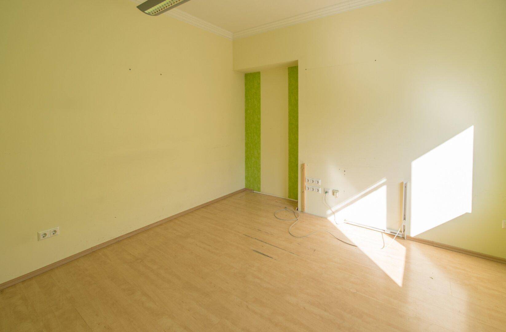 Helles Büro mit Laminatboden und grünen Akzenten, bietet eine freundliche Arbeitsumgebung.