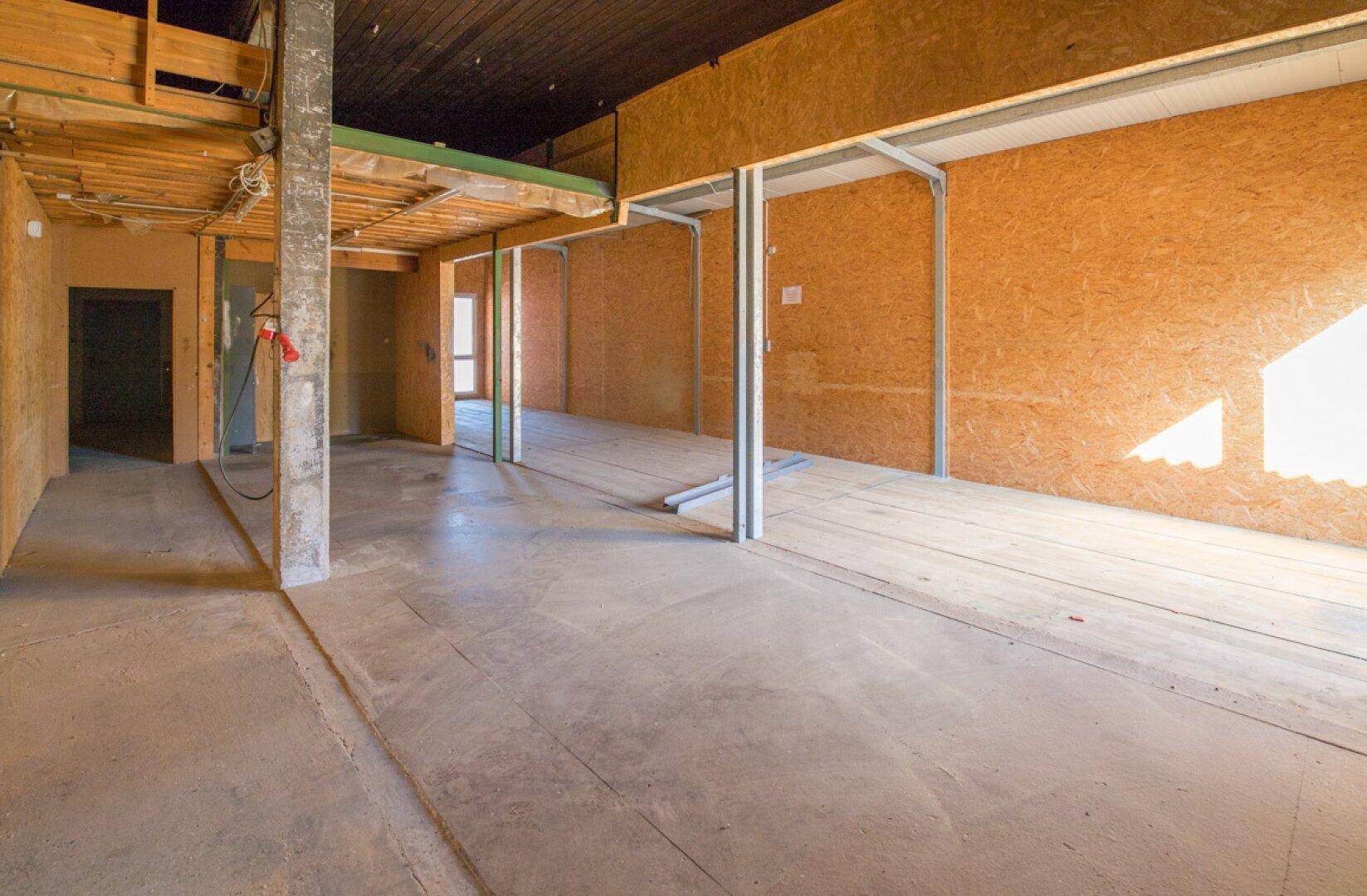 Große Lagerhalle mit Betonboden und Holzverkleidung, bietet viel Platz für verschiedene Zwecke.
