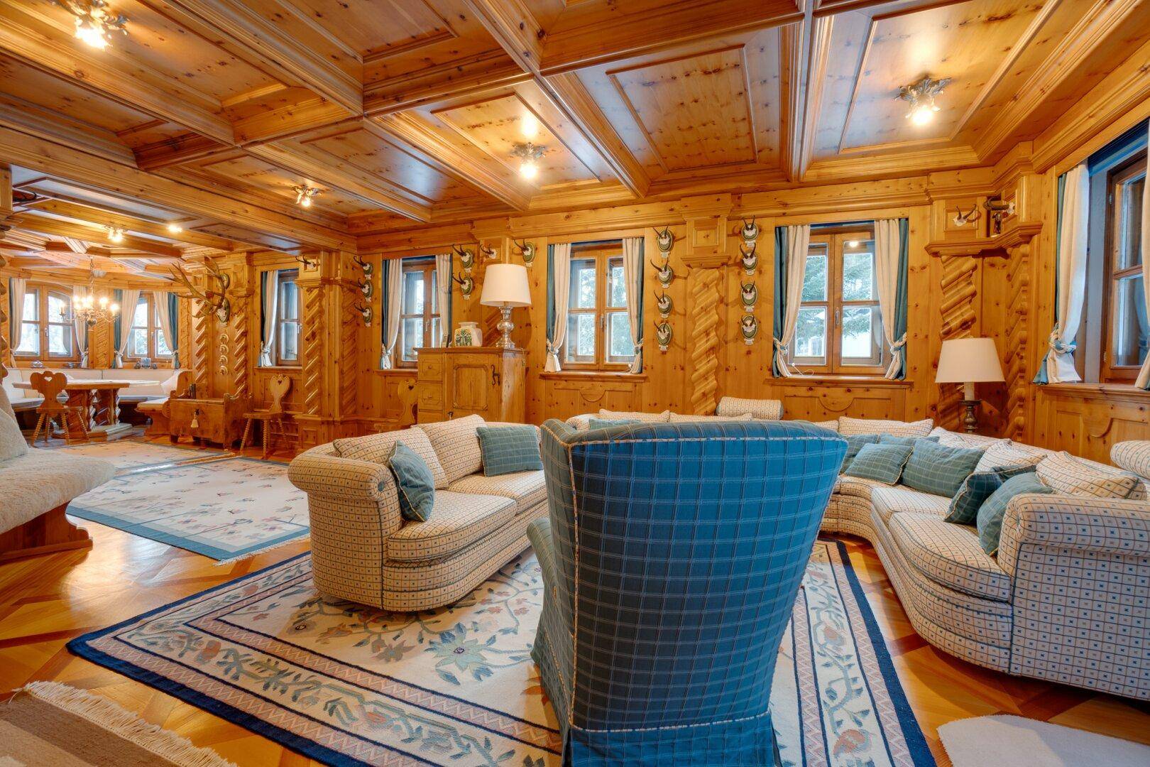Komfortables Wohnzimmer mit traditionellen Möbeln, Holzböden und reichlich Tageslicht, das den Raum erhellt.