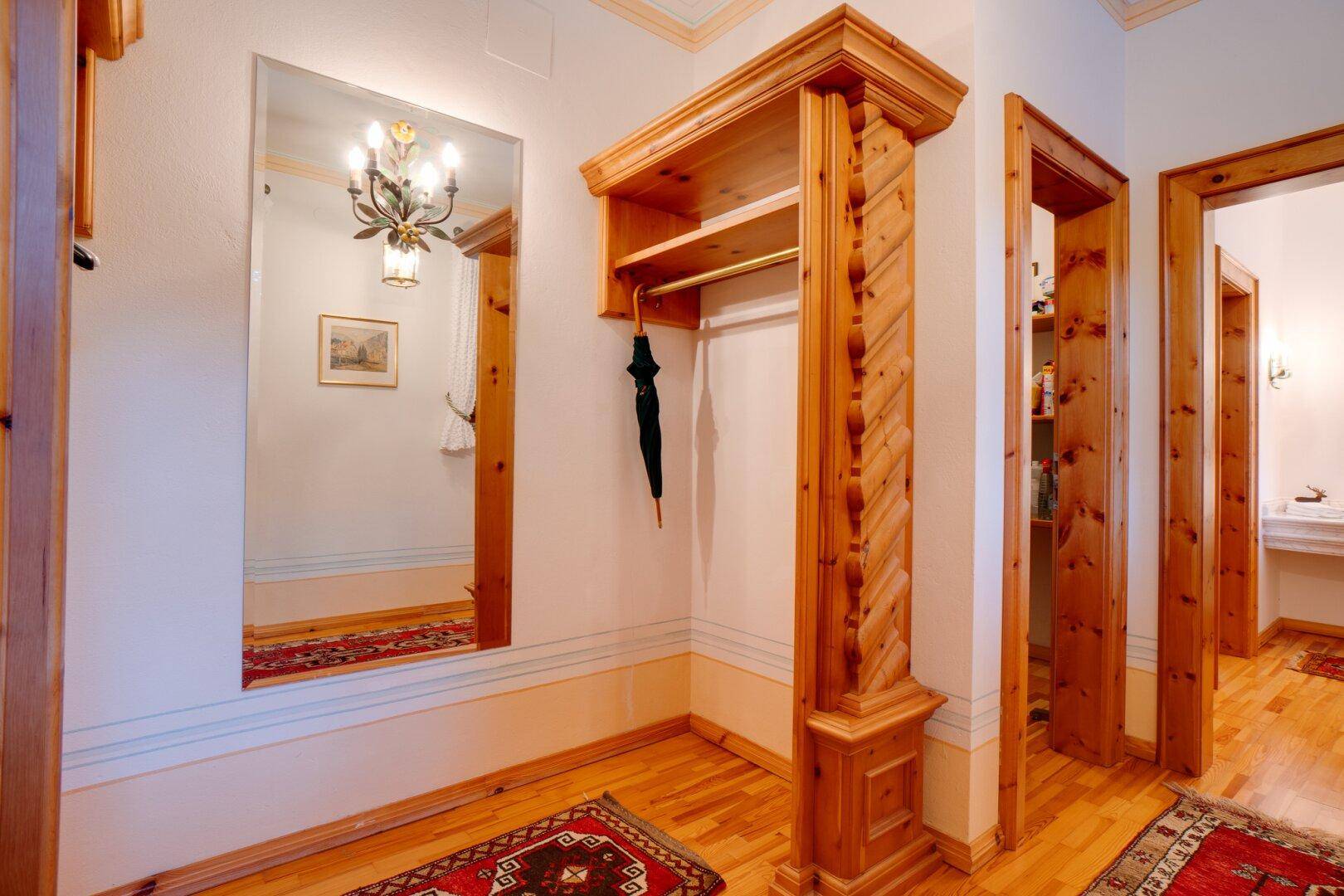 Heller Flur mit großem Spiegel, Garderobe aus Holz und traditionellen Teppichen, die den Eingangsbereich schmücken.