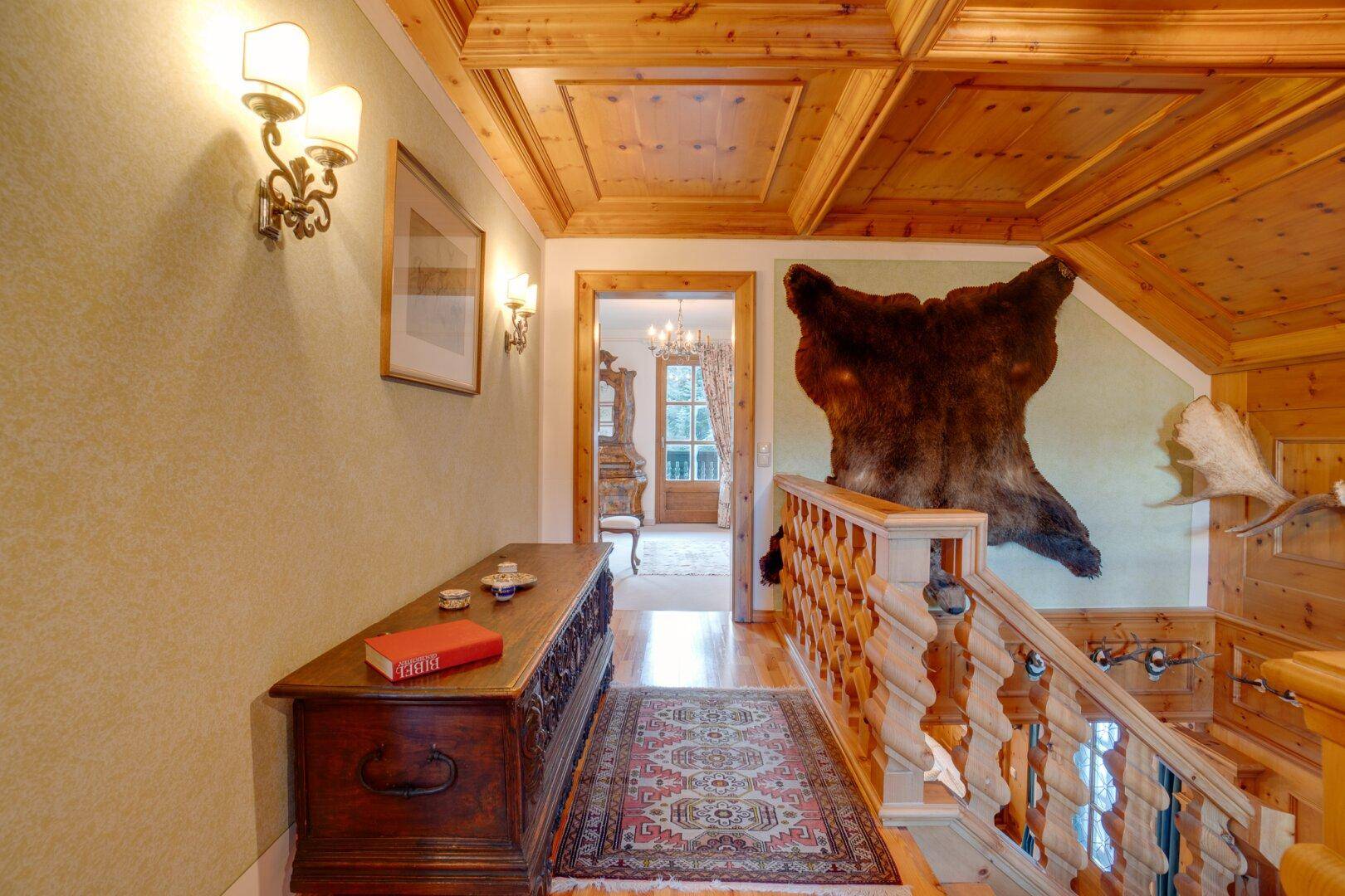 Oberer Flur mit Holzvertäfelung, Teppich und alpiner Dekoration, der zu weiteren Räumen führt.