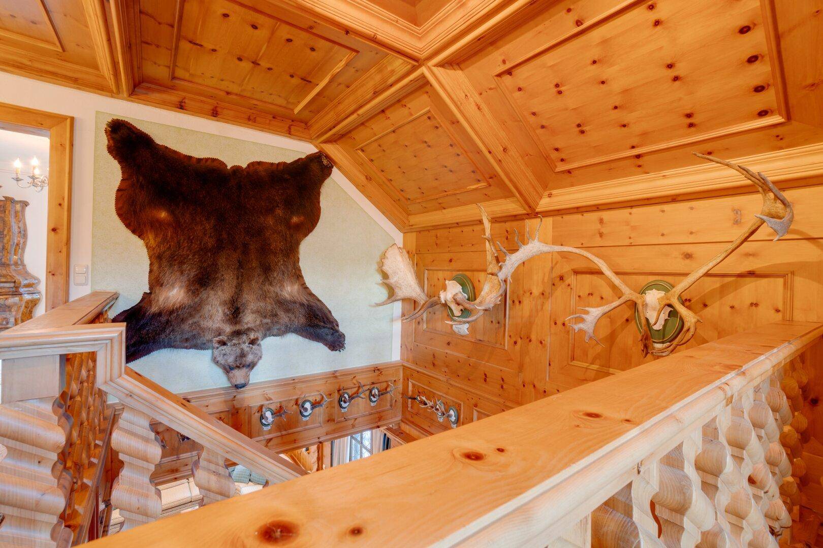 Detailansicht des oberen Flurs mit reichlich Holzvertäfelung und Jagdtrophäen an den Wänden, die den Charakter des Hauses prägen.