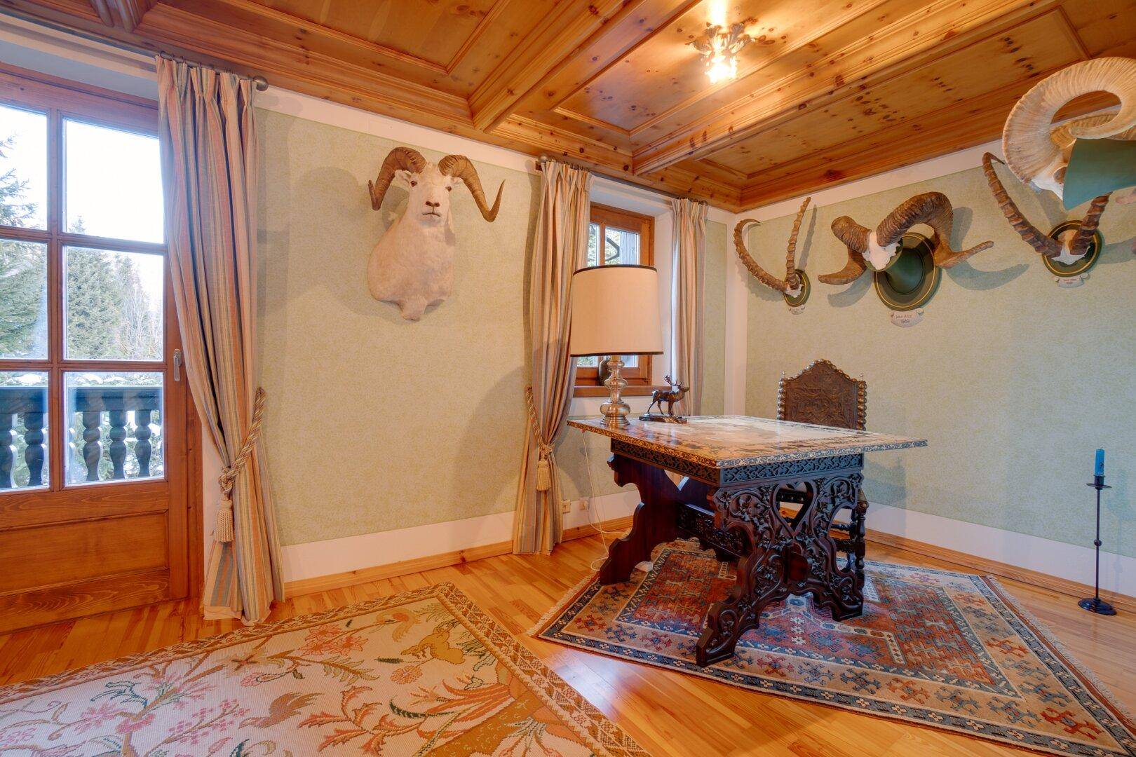 Arbeitszimmer mit Holzboden, traditionellem Schreibtisch und alpiner Dekoration, das eine ruhige Arbeitsatmosphäre bietet.