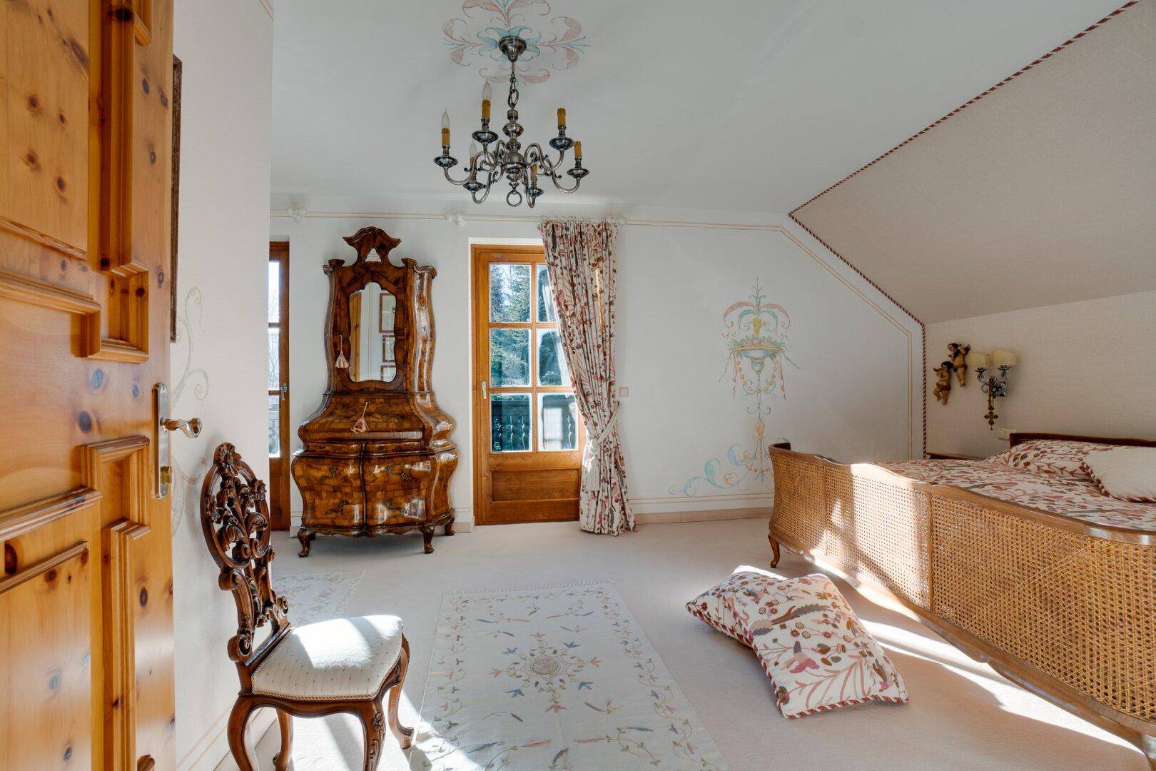 Helles Schlafzimmer mit Teppichboden, Himmelbett und Zugang zum Balkon, der einen schönen Ausblick bietet.
