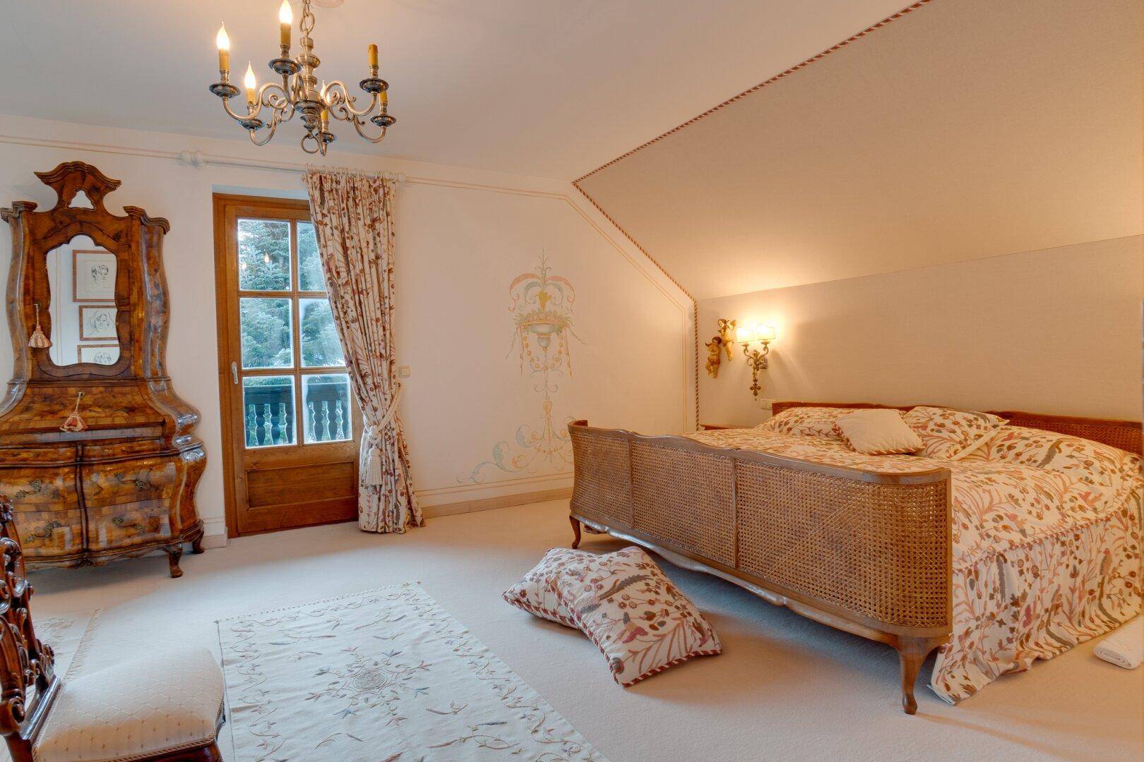 Gemütliches Schlafzimmer mit traditionellem Bett, Teppichboden und dekorativen Wandmalereien, die eine besondere Note verleihen.
