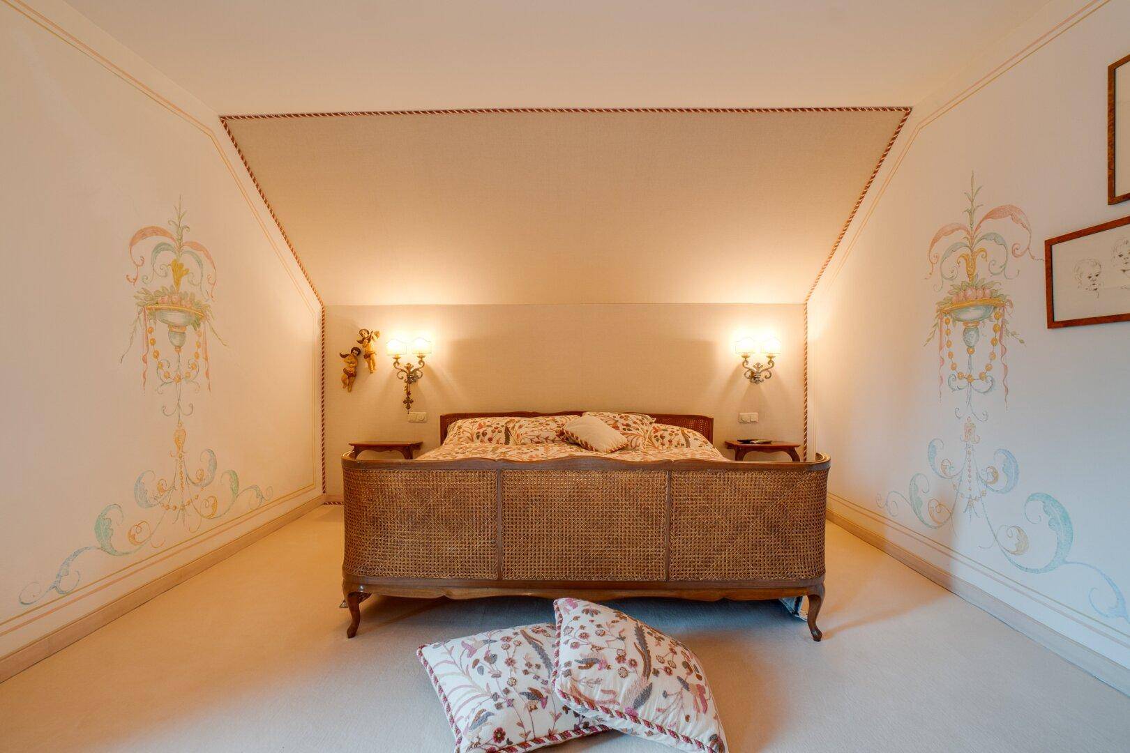 Schlafzimmer mit elegantem Bett, Teppichboden und kunstvollen Wanddekorationen, die den Raum verschönern.