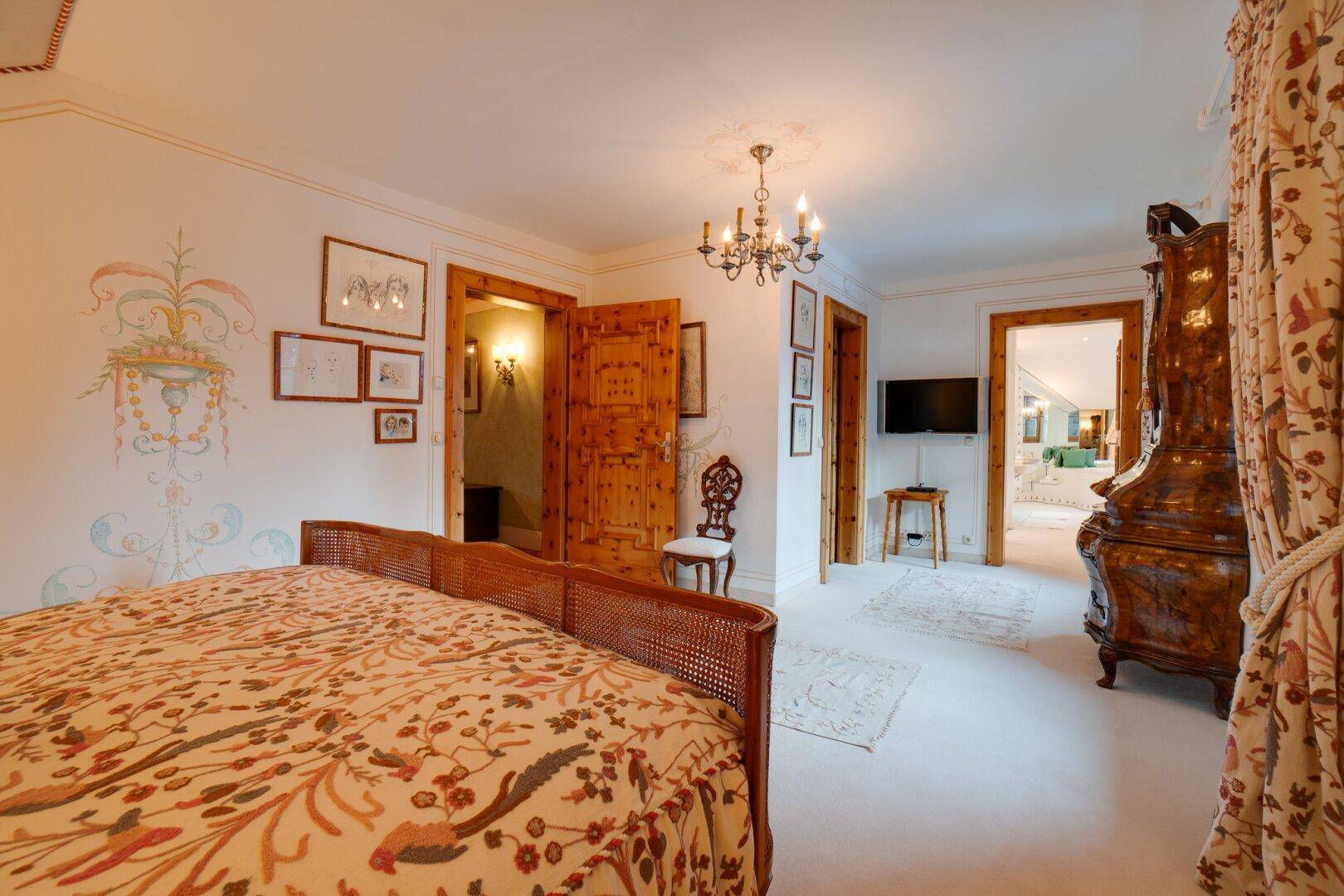 Geräumiges Schlafzimmer mit Teppichboden, antiken Möbeln und direktem Zugang zum luxuriösen Badezimmer.