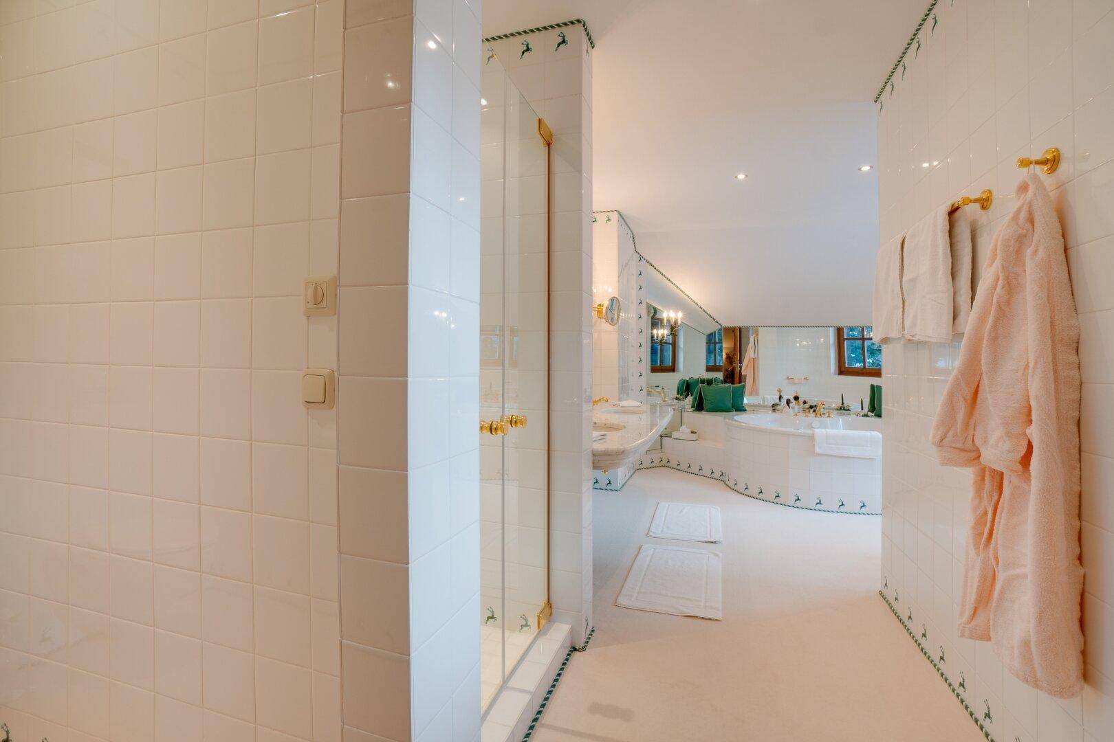 Luxuriöses Badezimmer mit Dusche, weißen Fliesen und goldenen Armaturen, die Eleganz ausstrahlen.