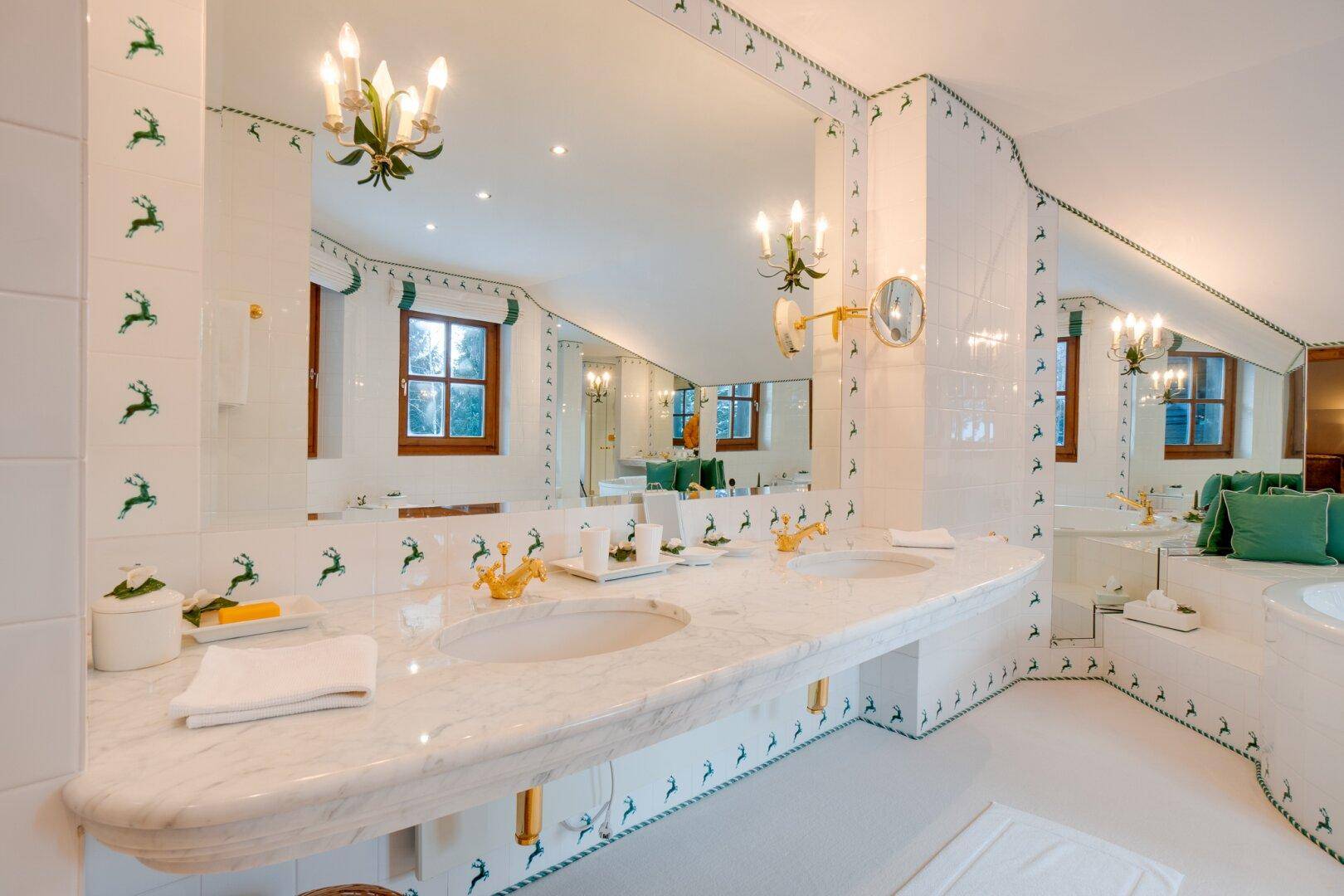 Elegantes Badezimmer mit Doppelwaschbecken aus Marmor und großen Spiegeln, die den Raum optisch vergrößern.
