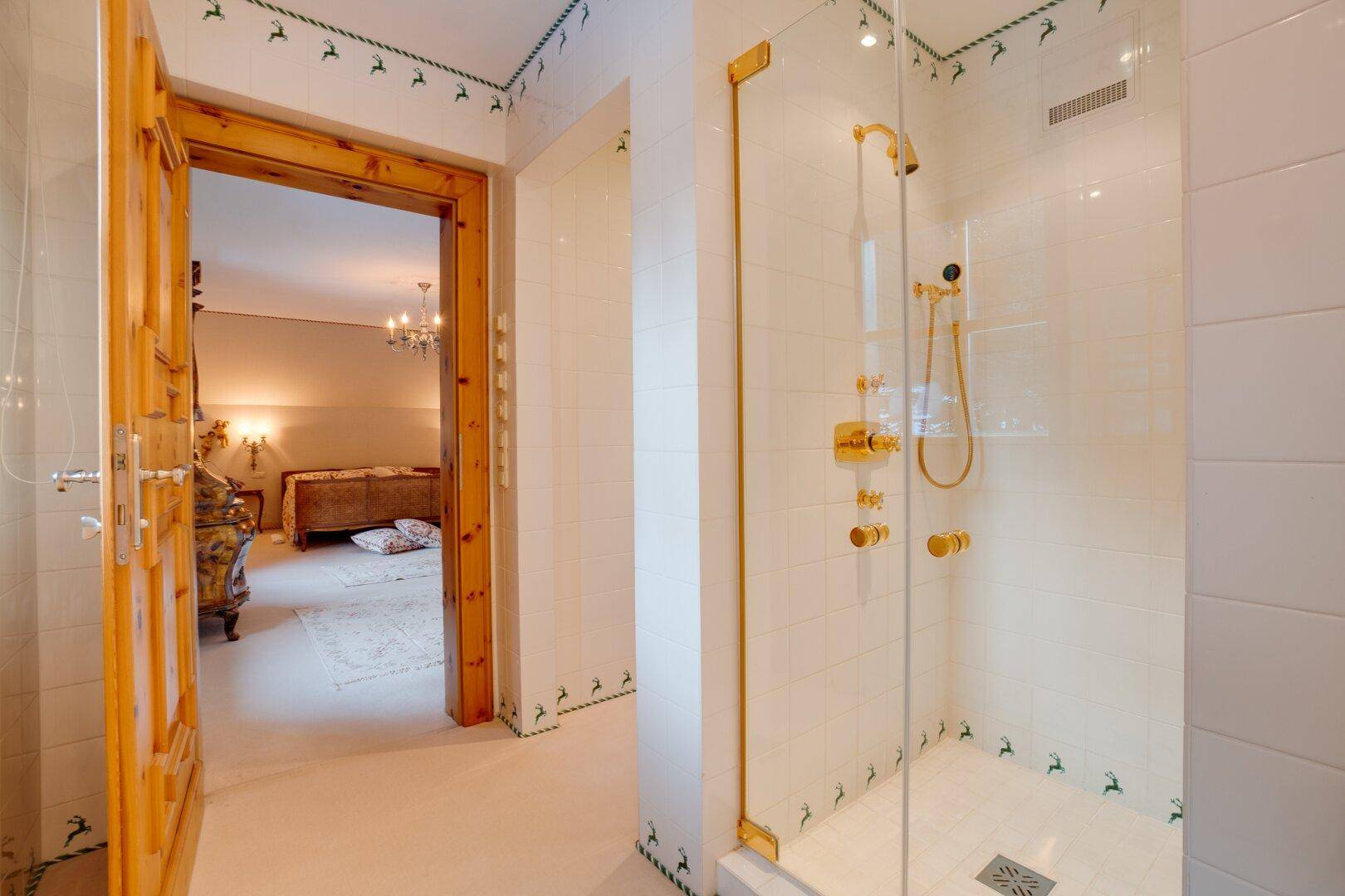 Moderne Dusche mit Glaswand und goldenen Armaturen, direkt vom Schlafzimmer zugänglich, für höchsten Komfort.