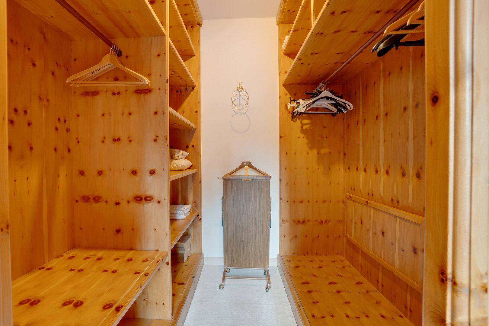 Begehbarer Kleiderschrank mit maßgefertigten Holzregalen und viel Stauraum, der Ordnung schafft.
