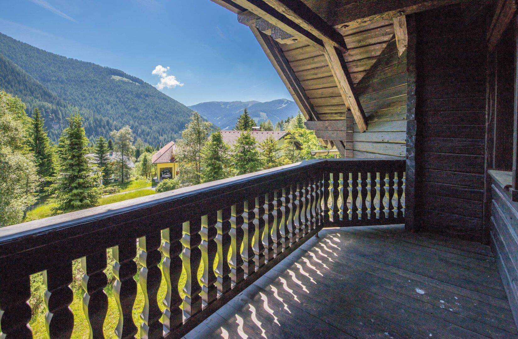 Sonniger Holzbalkon mit malerischem Blick auf die umliegenden Berge und das Tal, der zum Verweilen einlädt.