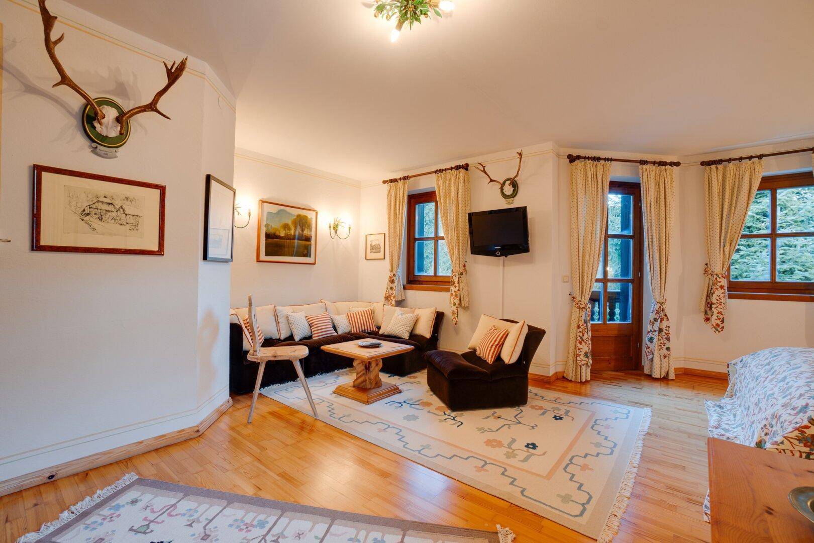 Gemütliches Schlafzimmer mit Holzboden, Sitzbereich und Zugang zum Balkon, der einen schönen Ausblick bietet.