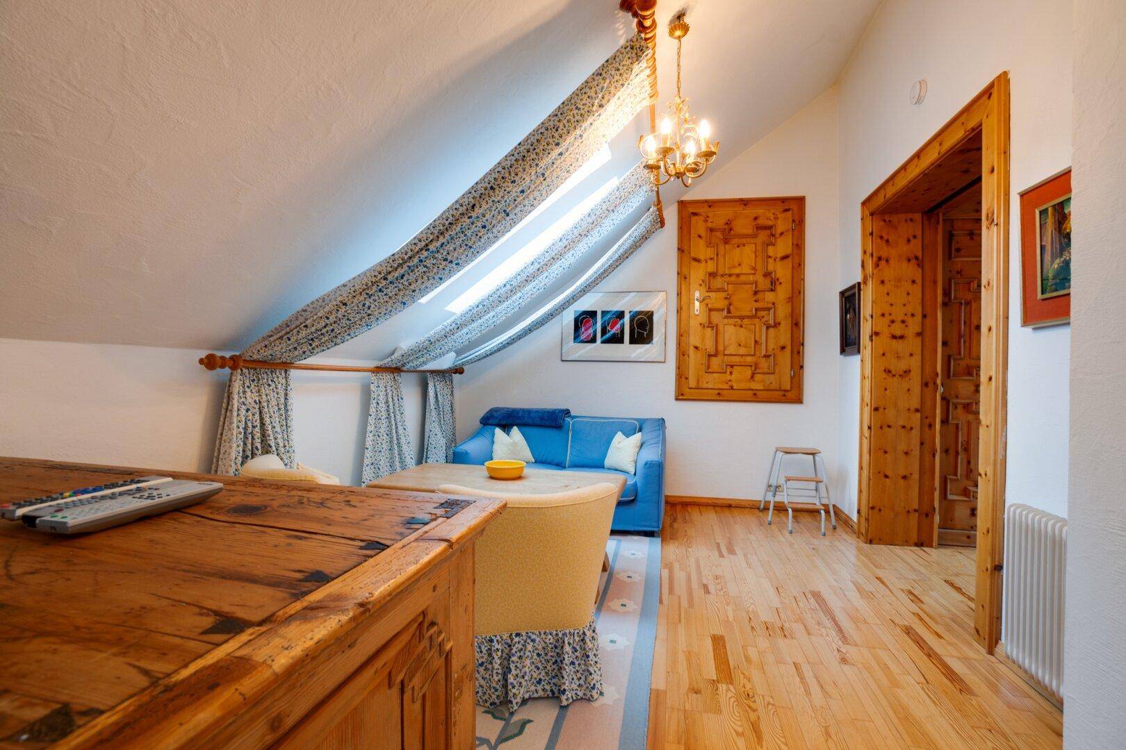 Dachgeschoss-Schlafzimmer mit Holzboden, Dachschrägen und Schiebetür zu einem weiteren Raum, der Flexibilität bietet.