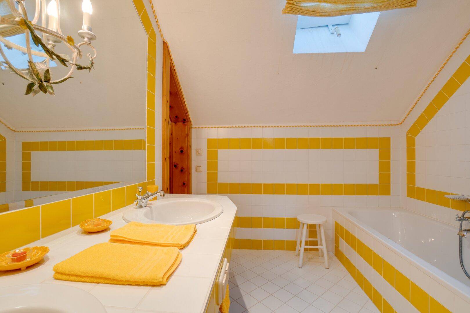 Separates WC im Dachgeschoss mit gelb-weißen Fliesen und Holzschrank, funktional und hell gestaltet.