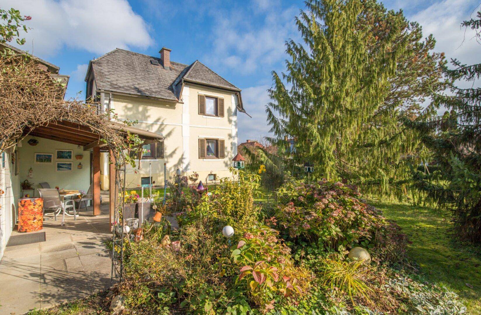Charmantes Haus mit überdachter Terrasse und einem liebevoll gestalteten Blumengarten.