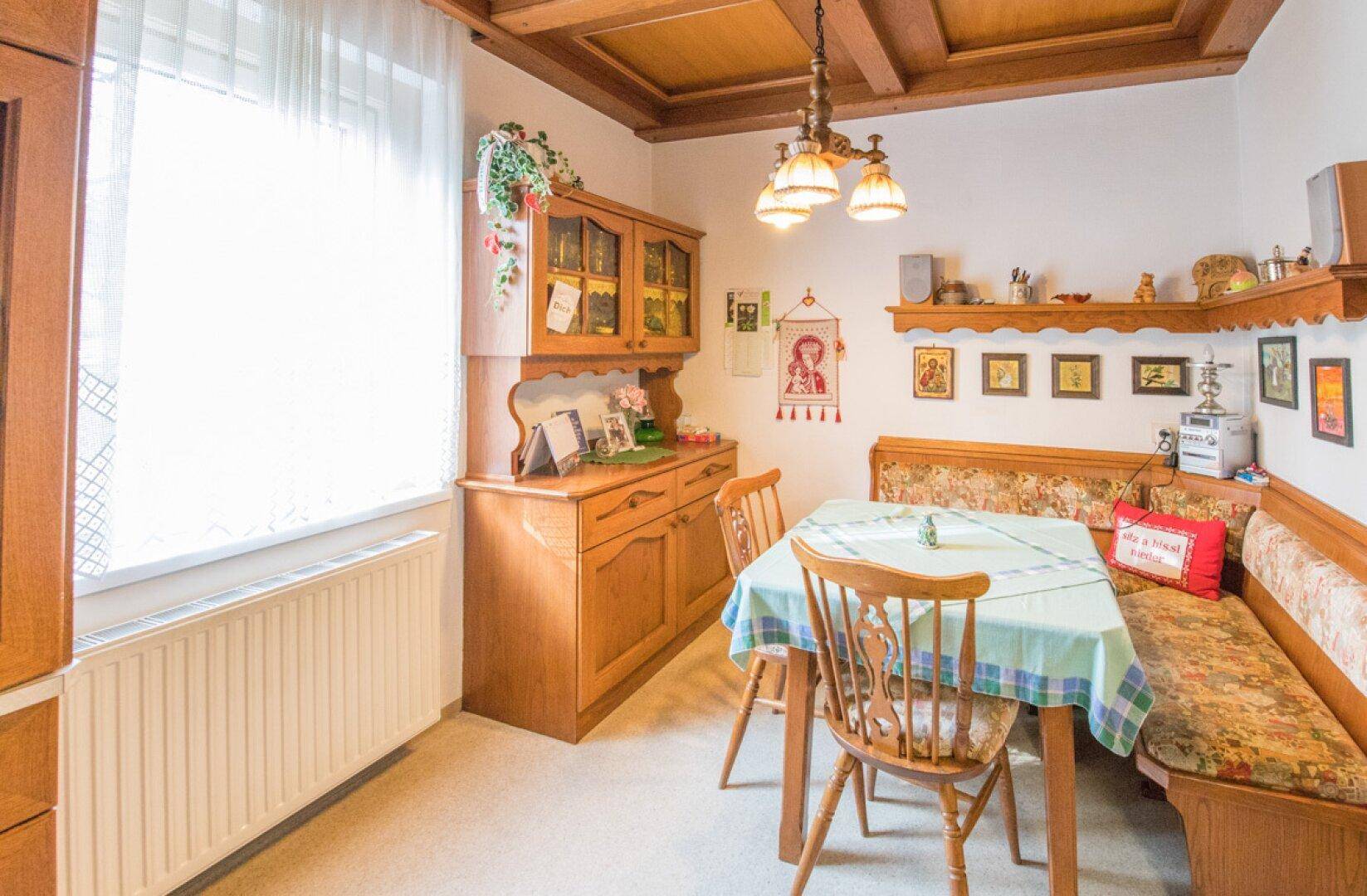 Gemütliche Küche mit Holzeinbauten, Essbereich und Durchgang zum Wohnzimmer.