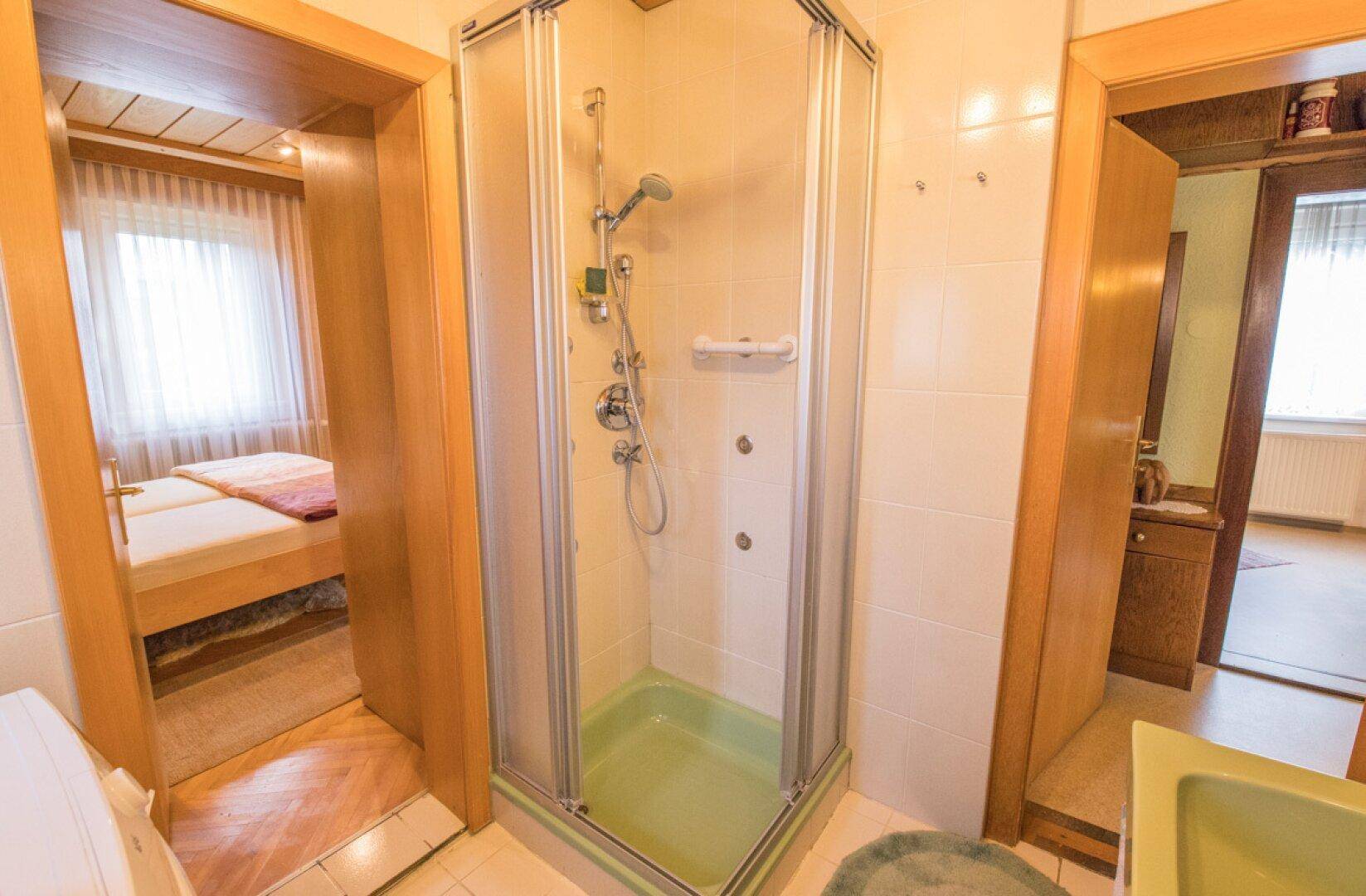 Funktionales Badezimmer mit Waschbecken, Duschkabine und Waschmaschine.