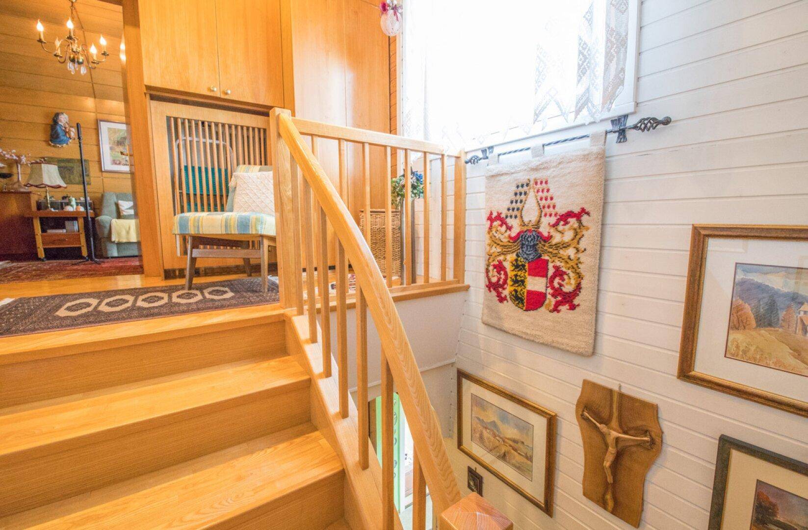 Treppenabsatz mit Sitzgelegenheit, Teppich und Blick auf die Holztreppe.