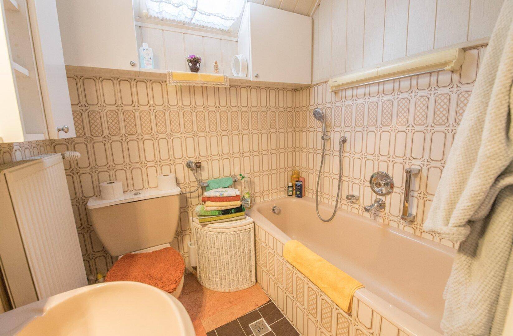 Gemütliches Wohnzimmer mit Holzvertäfelung, Sofa und Teppichboden.