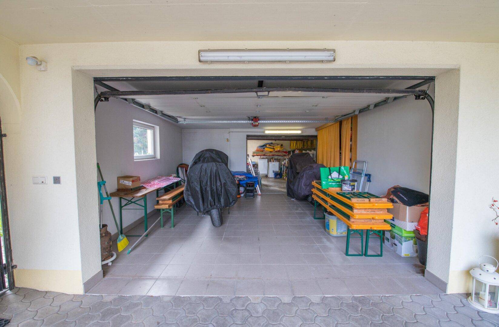 Garage mit viel Stauraum, Regalen und verschiedenen Werkzeugen und Geräten.