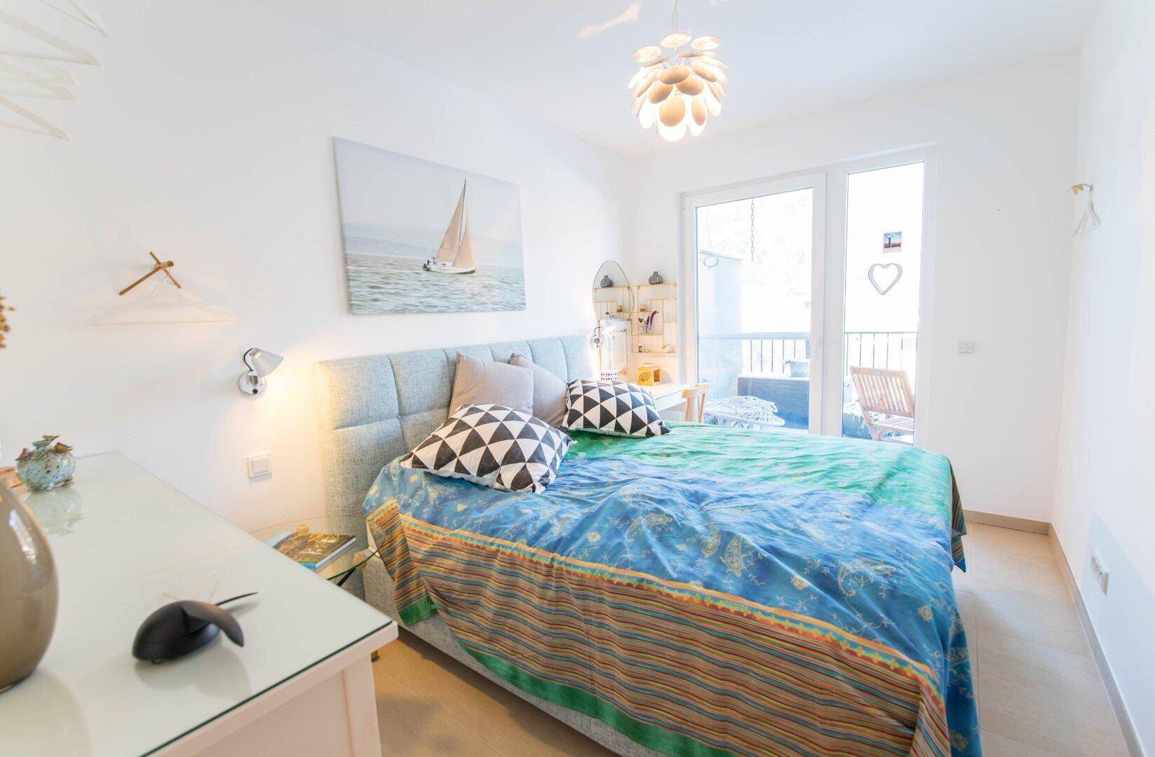 Helles Schlafzimmer mit Doppelbett, moderner Dekoration und Balkonzugang.