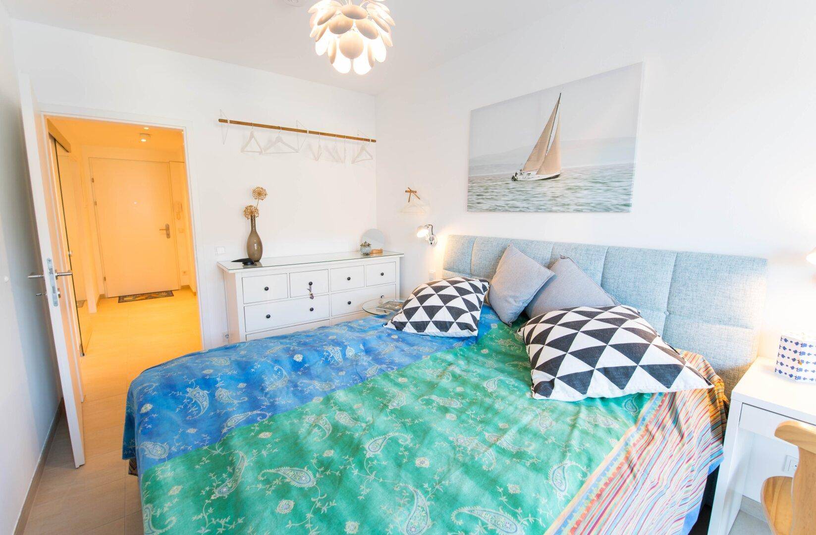 Gemütliches Schlafzimmer mit hellem Interieur und Zugang zum Flur.
