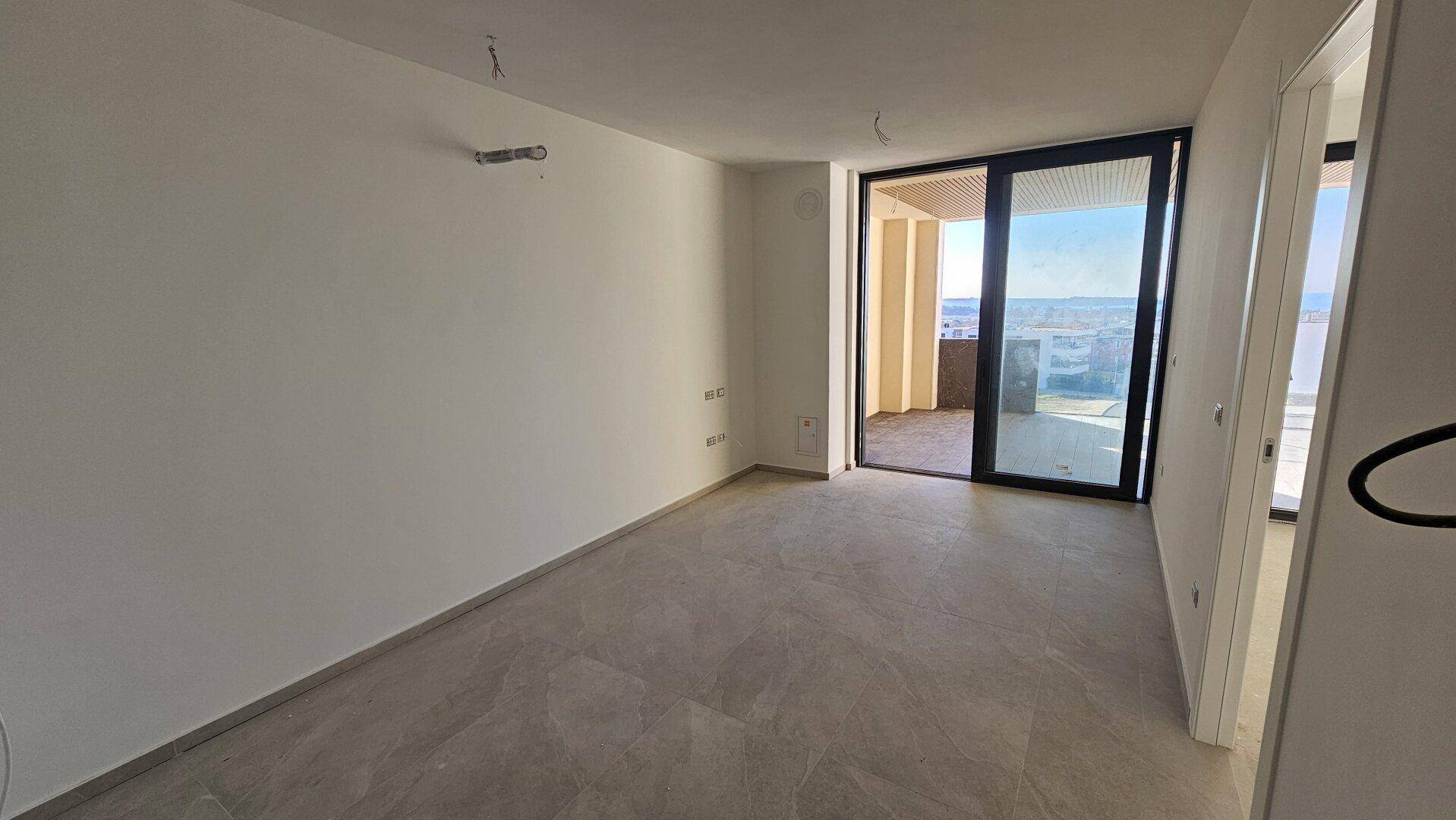 Geräumiger, unmöblierter Raum mit Fliesenboden und Zugang zu einem Außenbereich mit Aussicht.