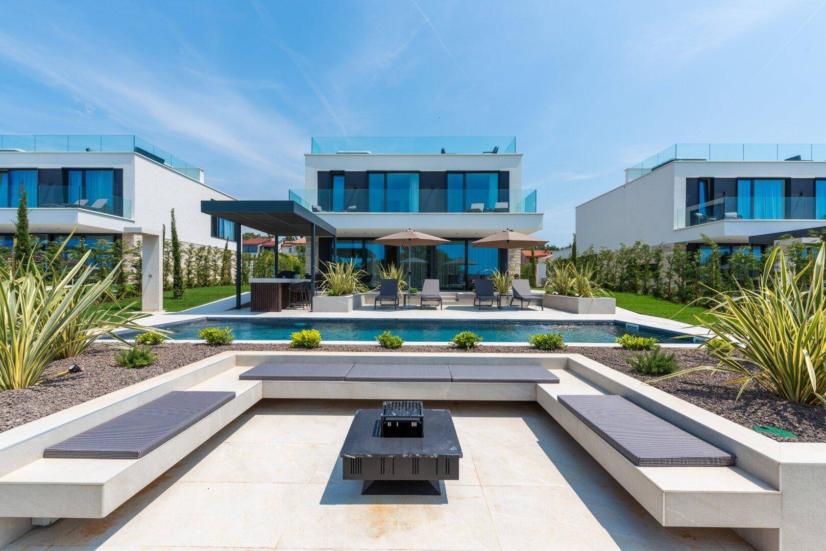 Elegante Villa mit großem Pool, Liegebereich und gemütlicher Feuerstelle im Außenbereich.