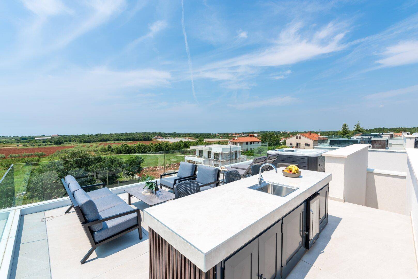 Geräumige Dachterrasse mit moderner Außenküche, Lounge-Bereich und weitem Blick ins Grüne.