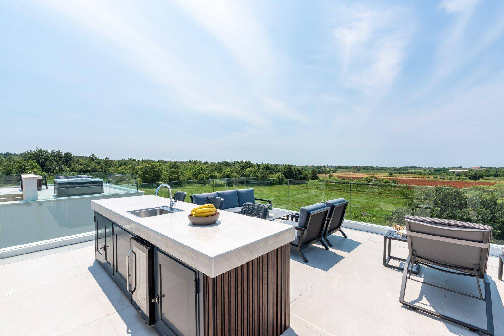Helle Dachterrasse mit stilvoller Außenküche, bequemen Lounge-Möbeln und Panoramablick.