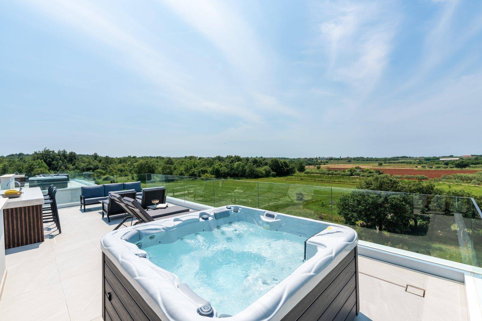 Luxuriöse Dachterrasse mit Whirlpool, Lounge-Möbeln und weitem Blick über die Landschaft.
