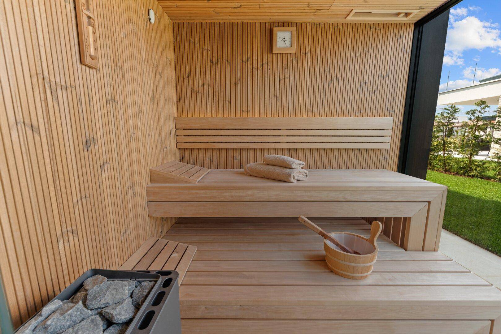 Private Holzsauna mit bequemen Bänken und traditionellem Saunaofen für entspannende Momente.