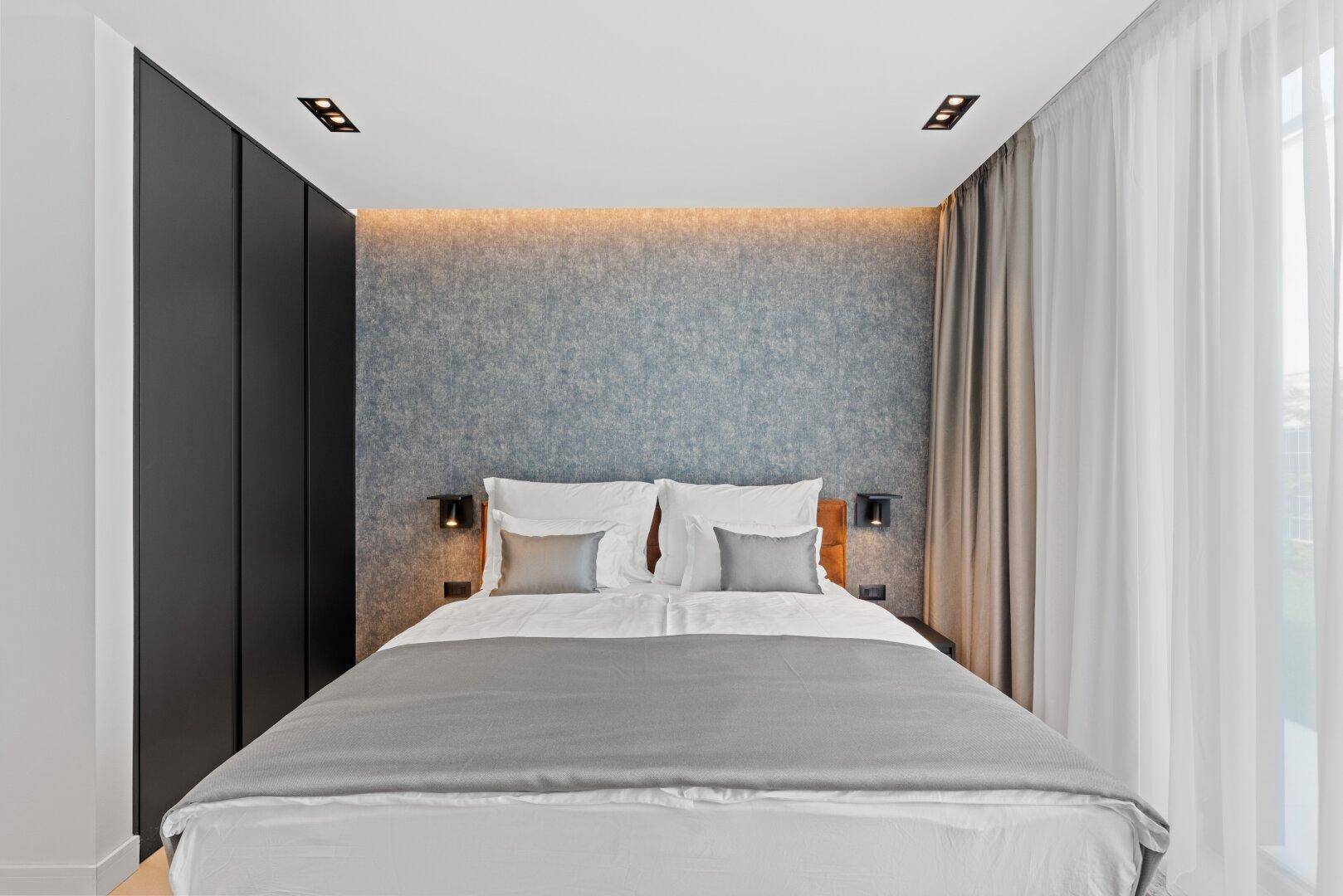 Modernes Schlafzimmer mit Doppelbett, indirekter Beleuchtung und integrierten Kleiderschränken.