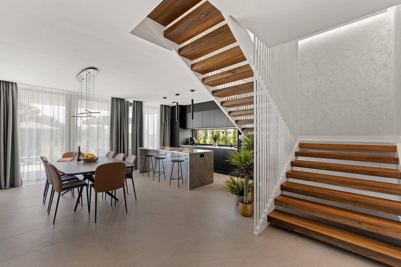 Offener Wohn- und Essbereich mit moderner Küche, Holzakzenten und eleganter Treppe.