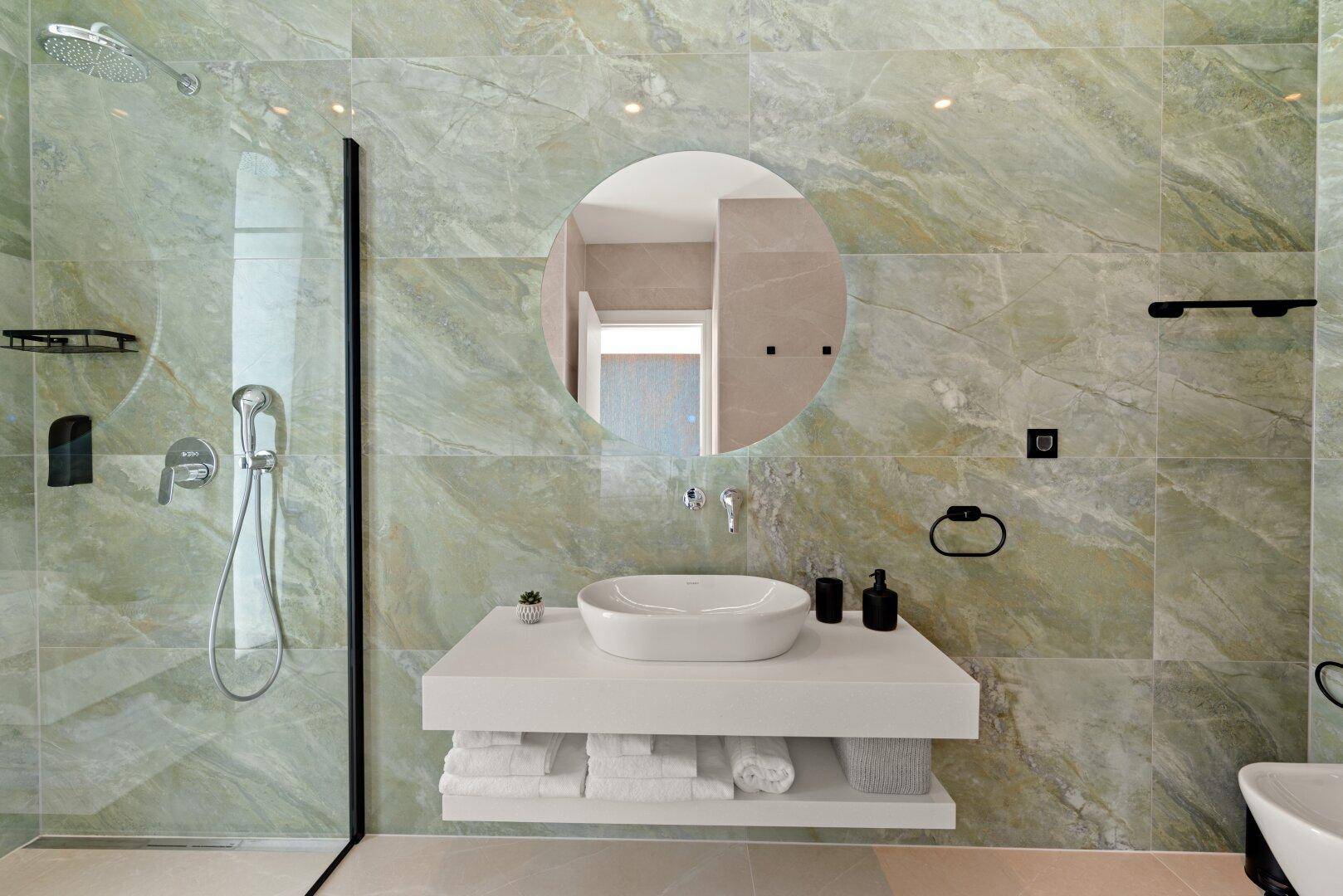 Elegantes Badezimmer mit grünen Marmorfliesen, modernem Waschbecken und begehbarer Dusche.