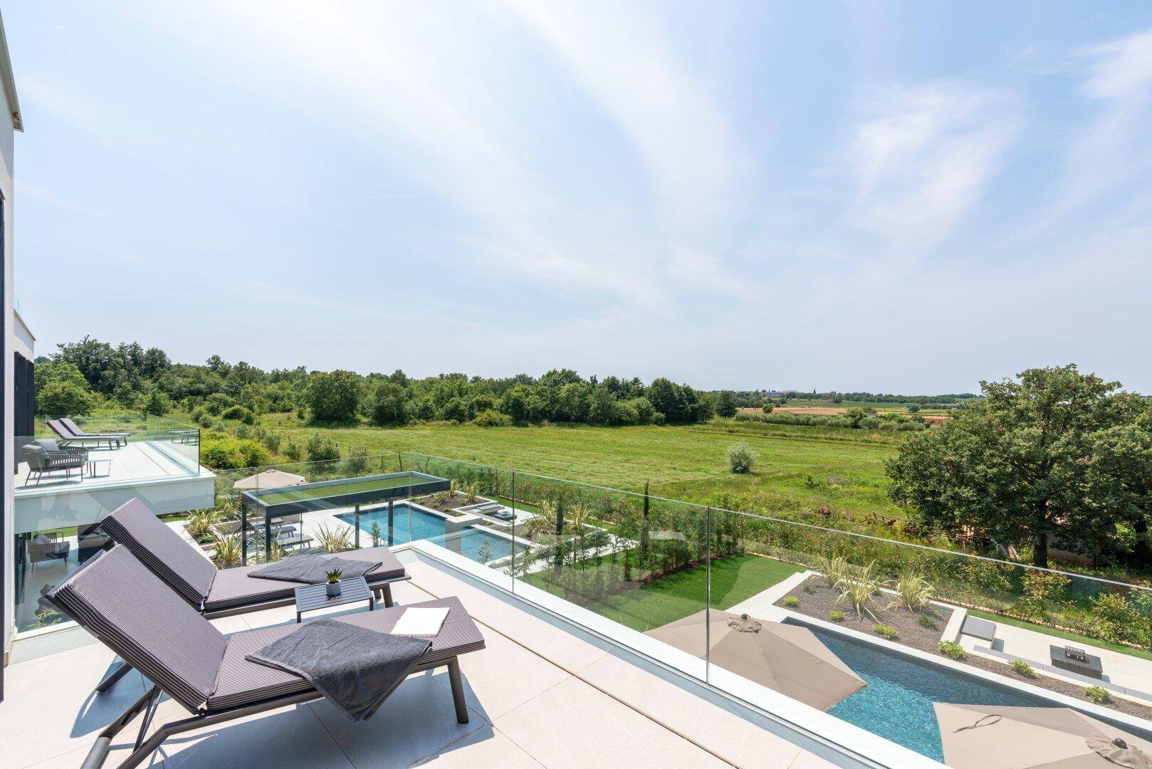Geräumiger Balkon mit Sonnenliegen und weitem Blick über die grüne Landschaft.