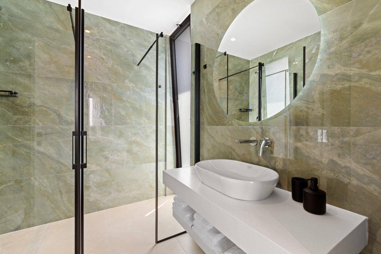 Helles Badezimmer mit begehbarer Dusche, modernem Waschbecken und großem Spiegel.