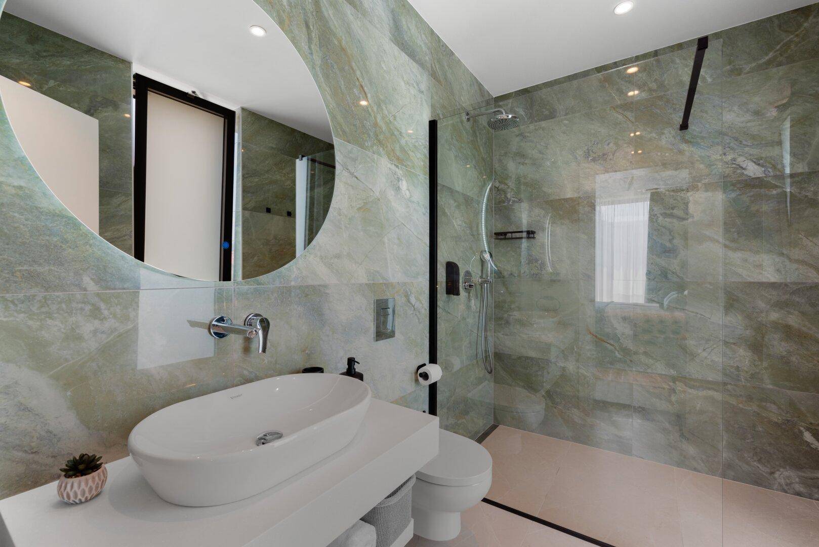Modernes Badezimmer mit begehbarer Dusche, Waschbecken und wandhängendem WC.